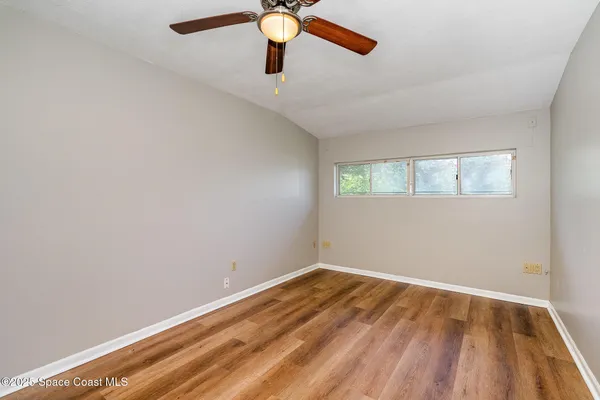 an empty room with a window and a ceiling fan