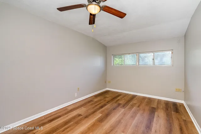 an empty room with a window and a ceiling fan