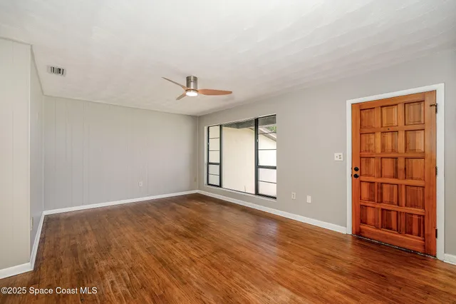 a view of an empty room with a window and wooden floor