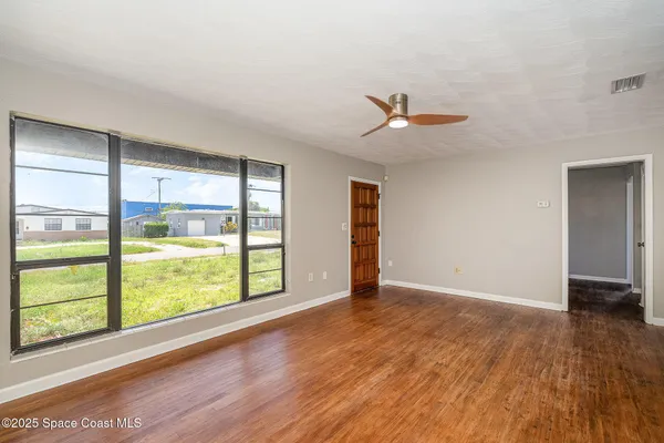 an empty room with wooden floor and windows