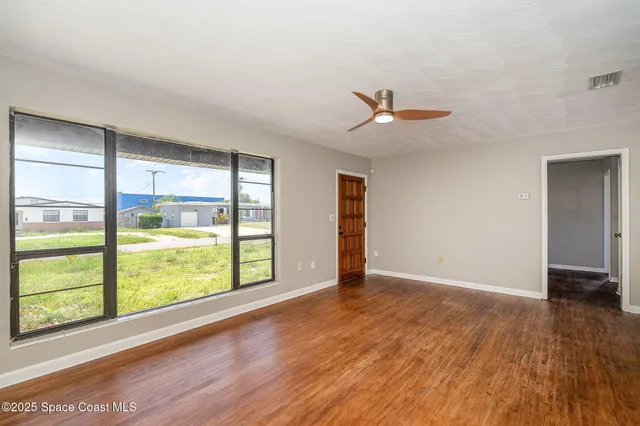 an empty room with wooden floor and windows