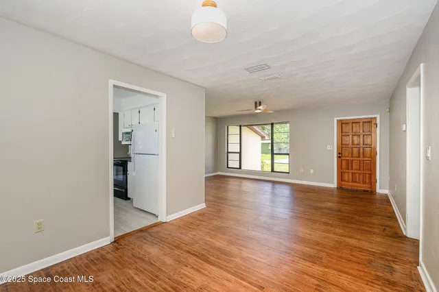 a view of an empty room with wooden floor and a window