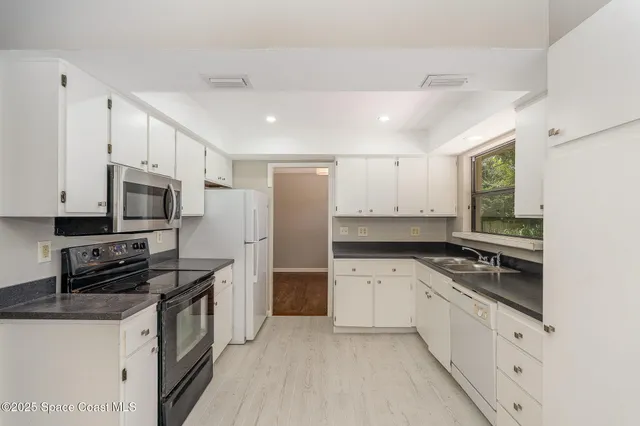 a kitchen with granite countertop a sink stove and refrigerator