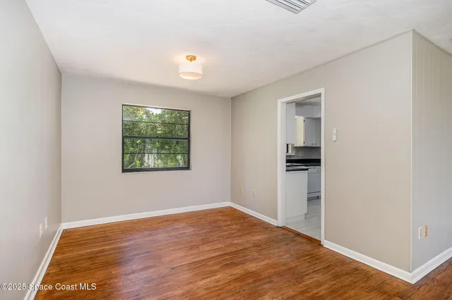 a view of empty room with wooden floor and window