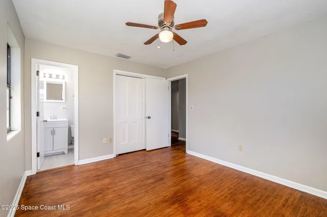 a view of a room with wooden floor and a ceiling fan