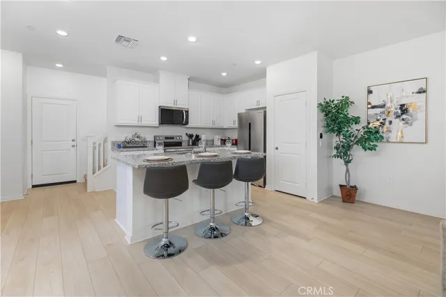 a view of a kitchen with kitchen island a counter top space a sink and stainless steel appliances