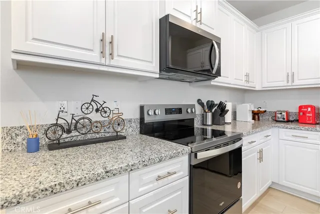 a kitchen with granite countertop white cabinets and a stove
