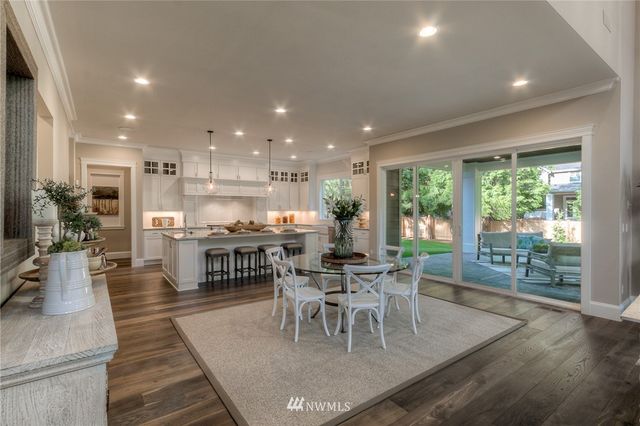 a dining room with stainless steel appliances furniture wooden floor and a kitchen view