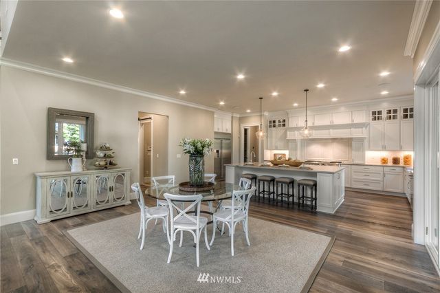 a kitchen with a dining table chairs wooden floor appliances and cabinets