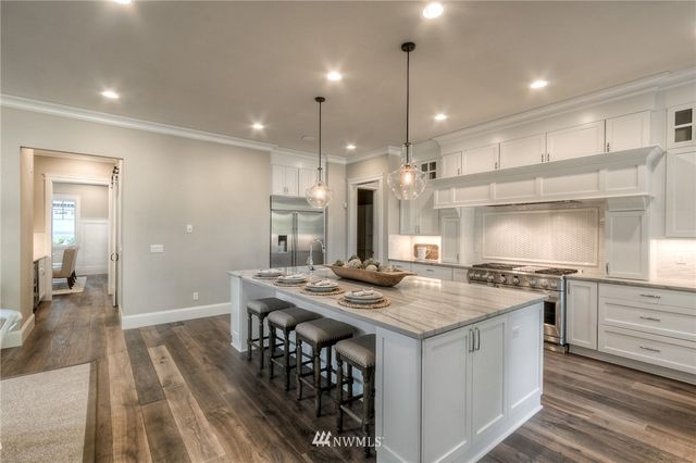 a kitchen with a stove a sink a refrigerator and chairs
