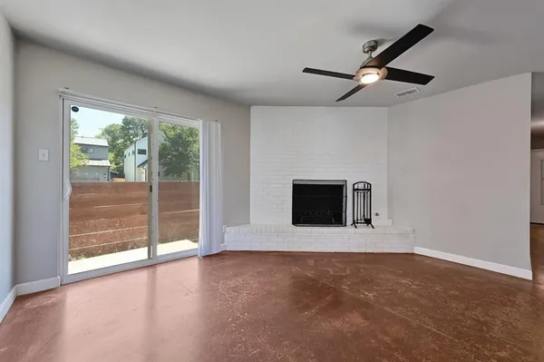 an empty room with floor to ceiling window and fireplace