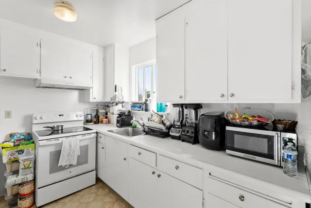 a kitchen with white cabinets and white appliances