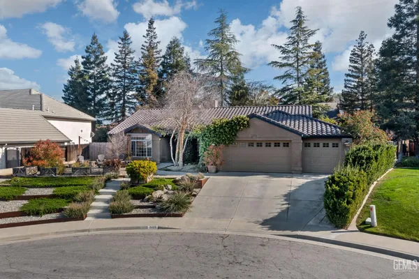 a front view of a house with a garden and tree