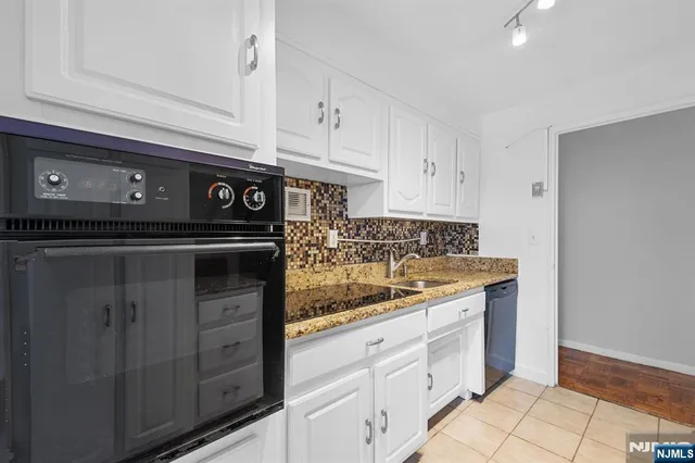a kitchen with granite countertop white cabinets and stainless steel appliances