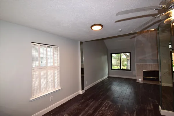 a view of an empty room with a window and wooden floor