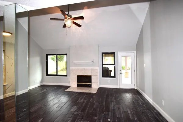 an empty room with wooden floor chandelier fan and windows