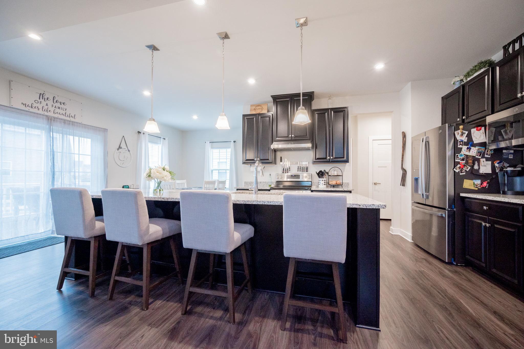772 Wallasey Drive Middletown, DE 19709 - Photo 21 of 60 a kitchen with stainless steel appliances kitchen island granite countertop a dining table chairs and a refrigerator