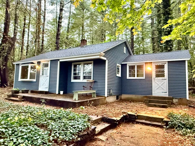 a backyard of a house with wooden fence and large trees
