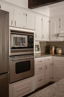 a kitchen with granite countertop white cabinets and stainless steel appliances