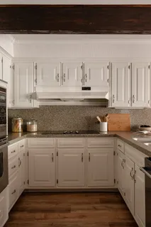 a kitchen with white cabinets and sink