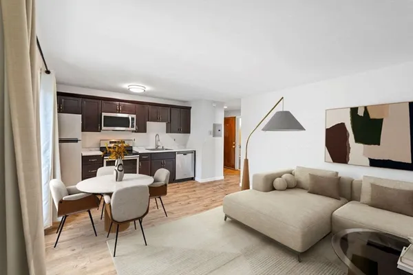 a living room with furniture kitchen view and a wooden floor