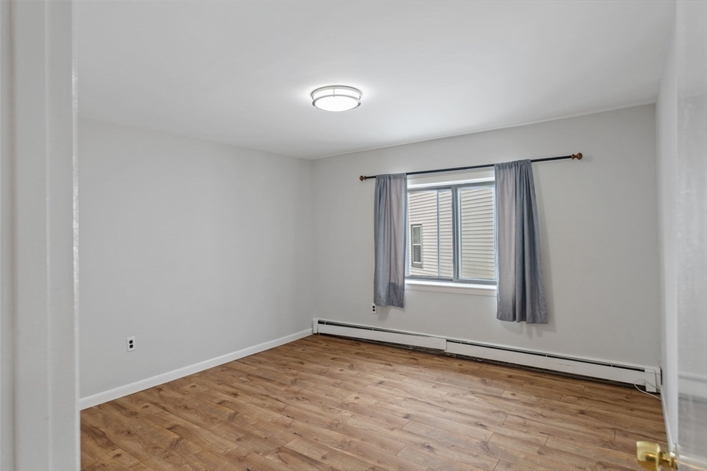 1030 Bennington Street, Unit 15 Boston, MA 02128 - Photo 7 of 20 an empty room with wooden floor and windows