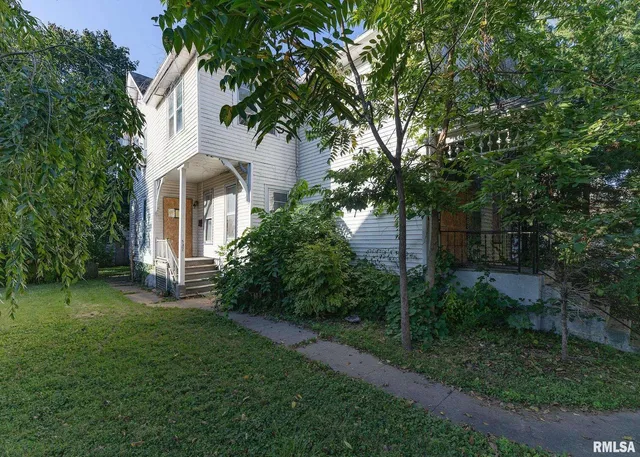 a front view of a house with a yard and tree