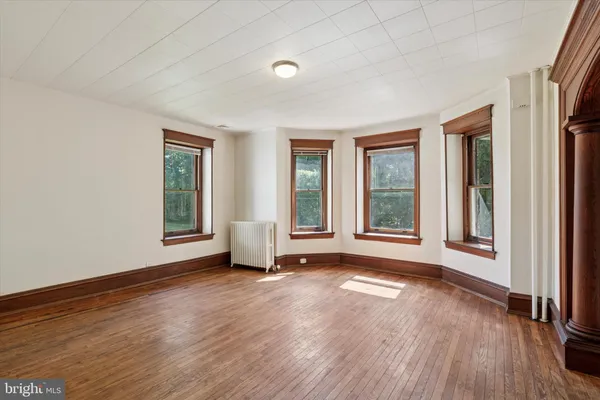 a view of an empty room with a window and wooden floor