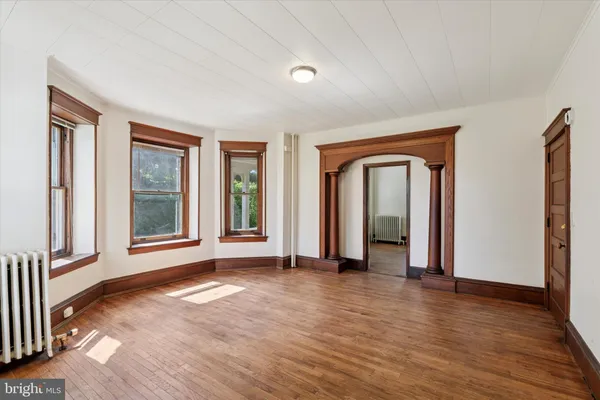 a view of an empty room with window and wooden floor