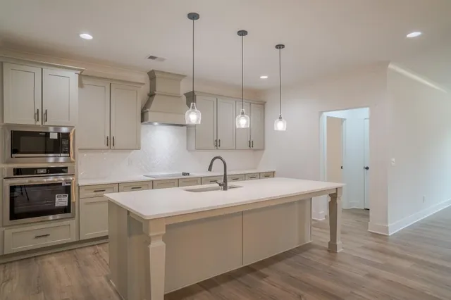 a kitchen with a sink a stove a microwave and wooden floor