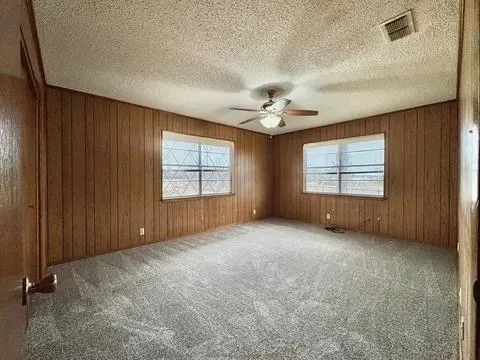 an empty room with windows and chandelier fan