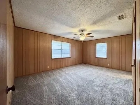 an empty room with windows and fan