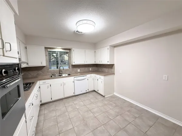 a large white kitchen with a sink and cabinets