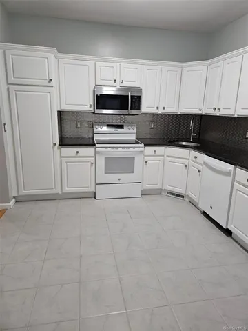 a kitchen with granite countertop white cabinets and stainless steel appliances
