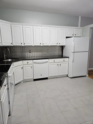 a kitchen with granite countertop white cabinets and white appliances