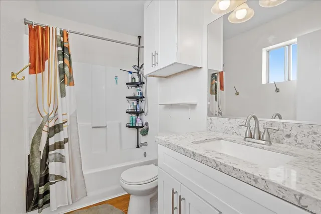a bathroom with a granite countertop sink toilet and shower