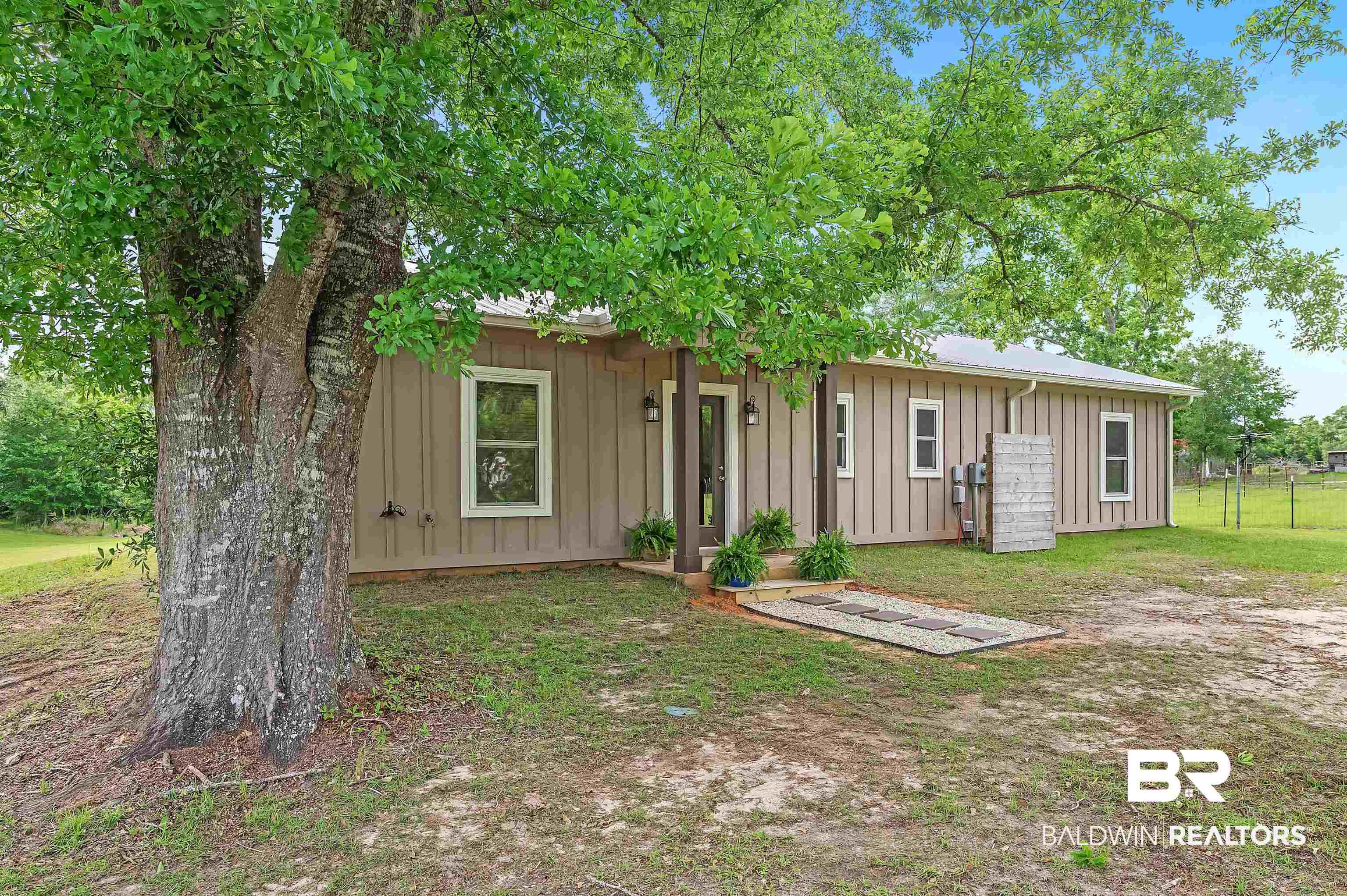 13827 County Road 83 Elberta, AL 36530 - Photo 5 of 38 View of front facade with board and batten siding and fence