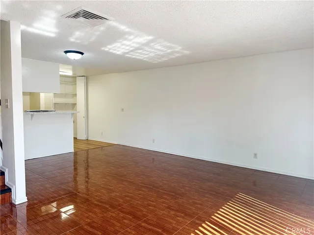 en empty room with wooden floor and kitchen view