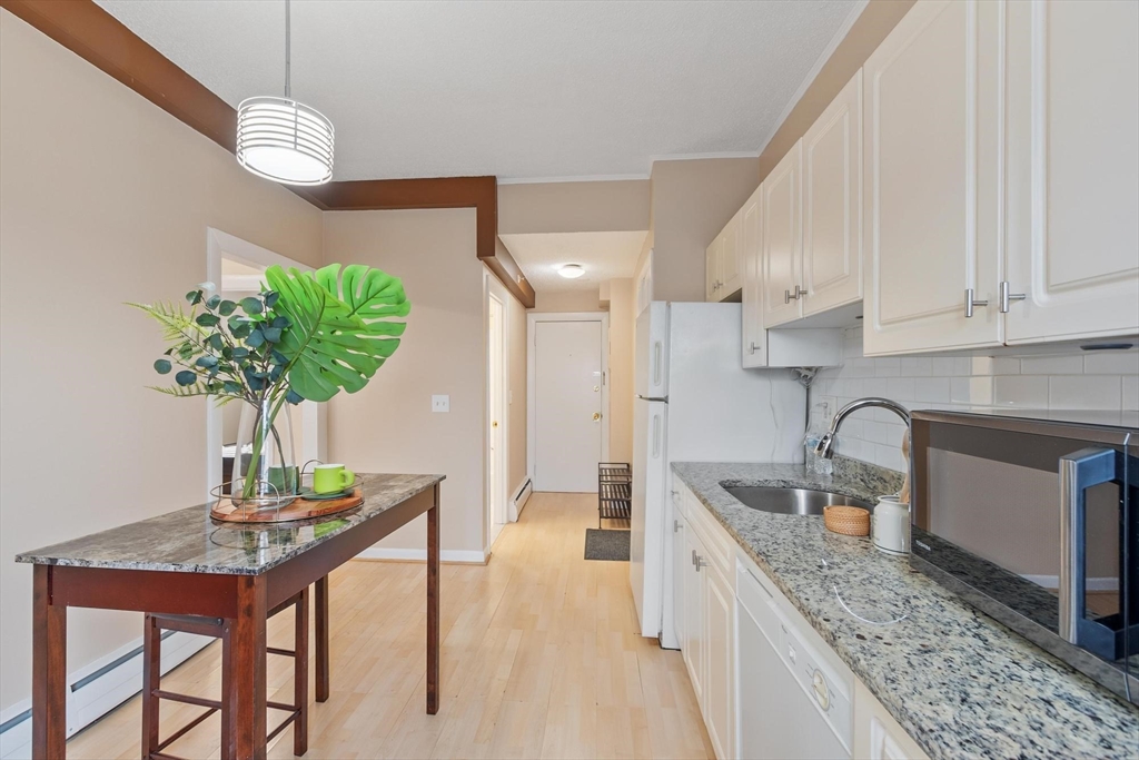 793 Main Street, Unit 1 Malden, MA 02148 - Photo 2 of 8 a kitchen with stainless steel appliances granite countertop a sink a kitchen island a stove a dining table and chairs with wooden floor