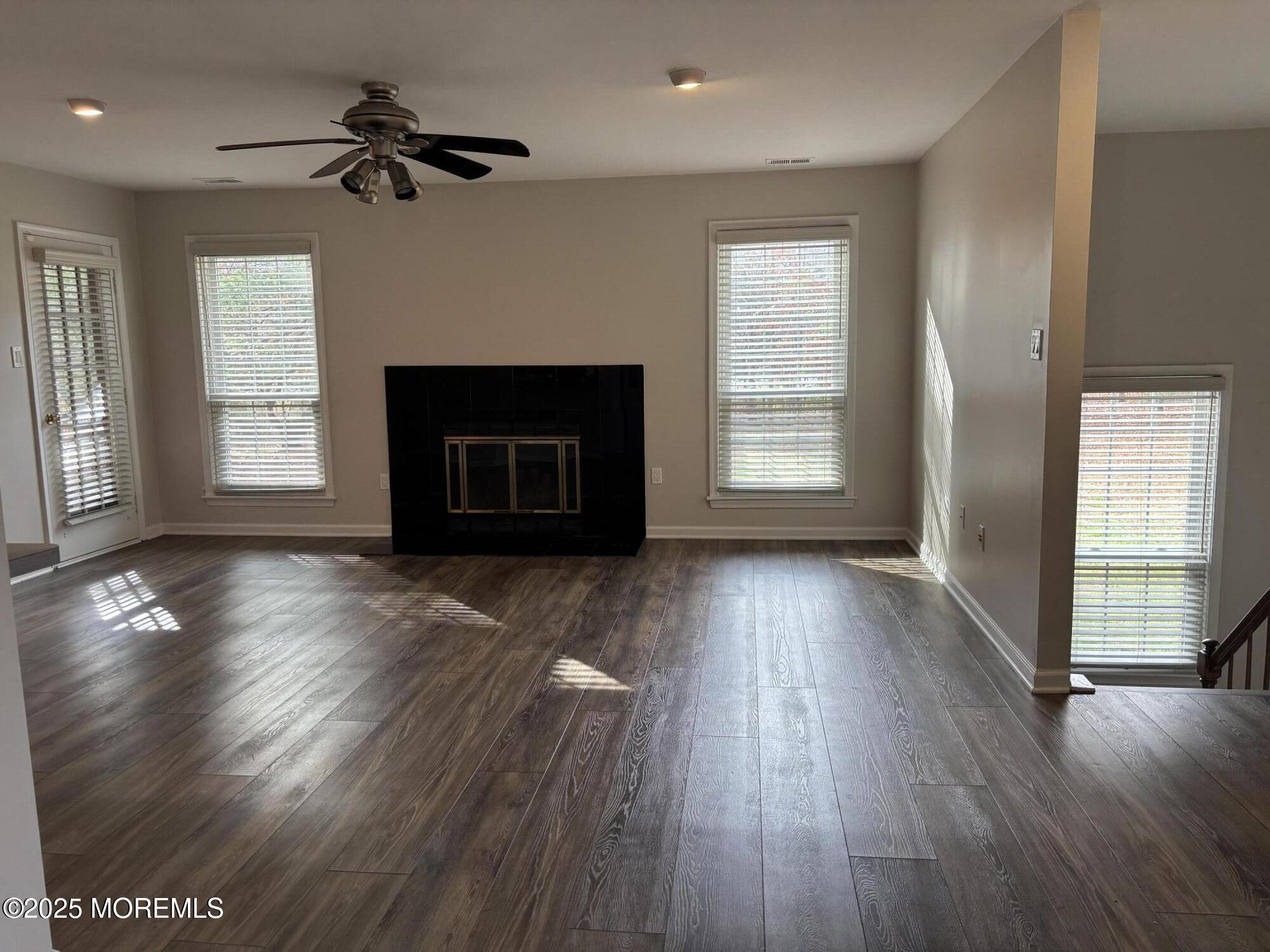 481 Hawthorne Place Morganville, NJ 07751 - Photo 8 of 36 an empty room with wooden floor fireplace and windows