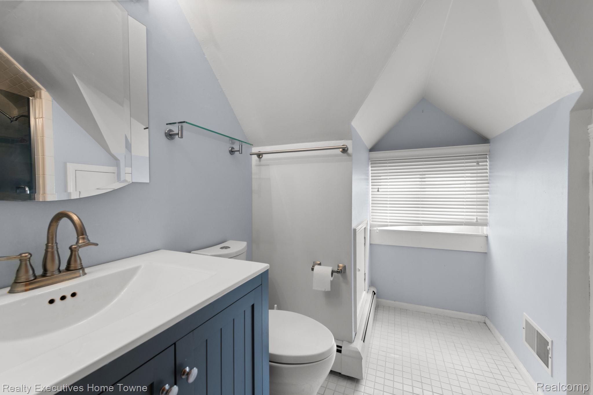 8308 Lakeshore Road Fort Gratiot, MI 48059 - Photo 72 of 79 Bathroom featuring a dark blue vanity with a white countertop and integrated sink, bronze-finish faucet, and a wall-mounted medicine cabinet