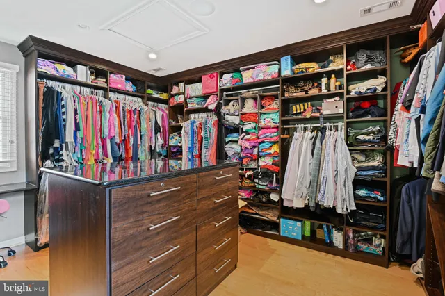 a view of walk in closet with clothes and shoes