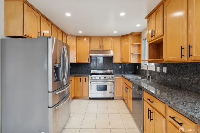 a kitchen with stainless steel appliances kitchen island granite countertop a refrigerator and a stove top oven