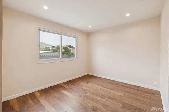 an empty room with wooden floor and entrance