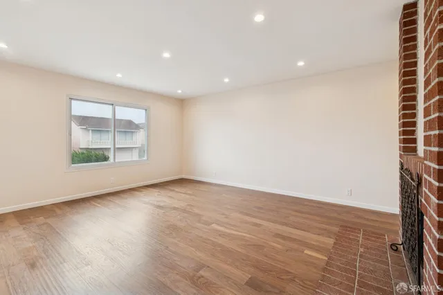 a view of a kitchen with refrigerator and wooden floor