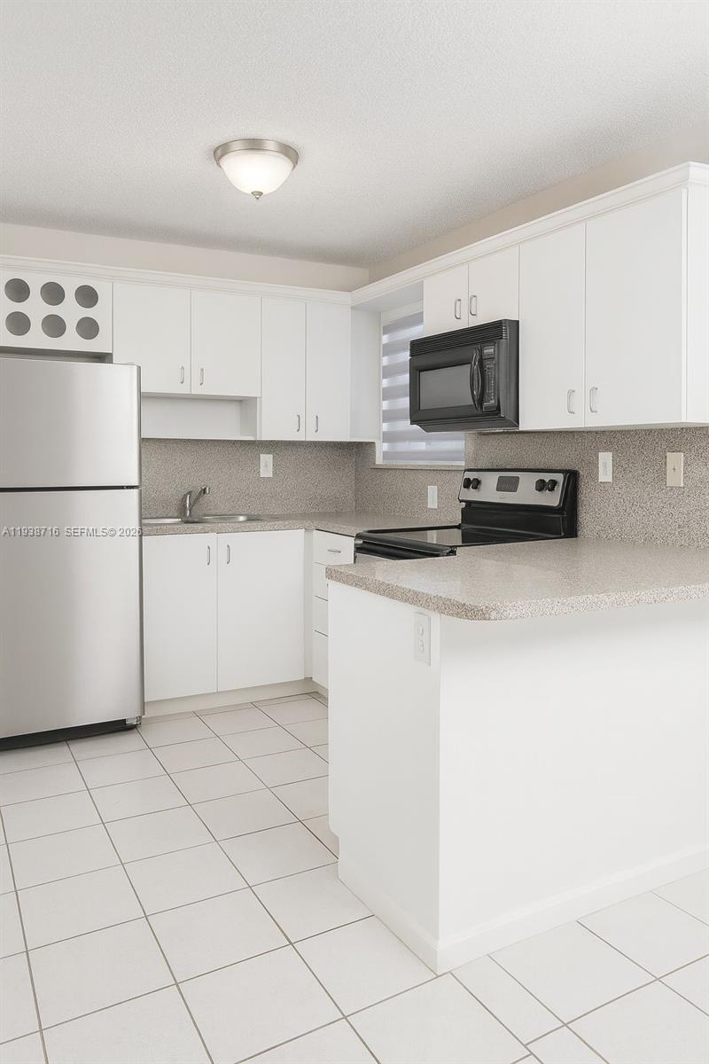 a kitchen with a refrigerator a stove top oven and white cabinets