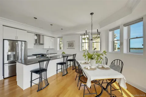 a kitchen with granite countertop a dining table chairs refrigerator and wooden floor