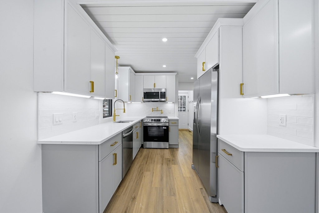 26 Rivulet Street Uxbridge, MA 01569 - Photo 9 of 41 a kitchen with stainless steel appliances a refrigerator oven a sink dishwasher and white cabinets with wooden floor