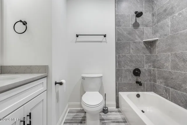 a bathroom with a granite countertop toilet a sink and a bathtub