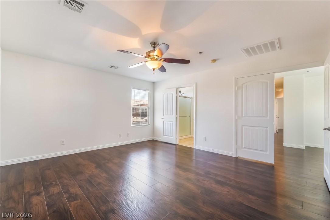 3175 Via Seranova Henderson, NV 89044 - Photo 21 of 45 This airy primary bedroom features rich hardwood flooring and a ceiling fan, offering a comfortable retreat.